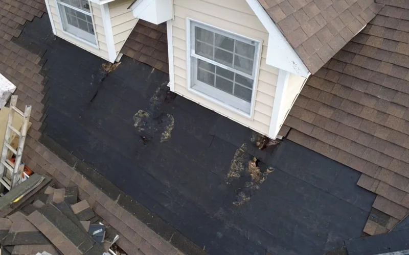 Roof repair in progress with the old shingles stripped and underlayment exposed