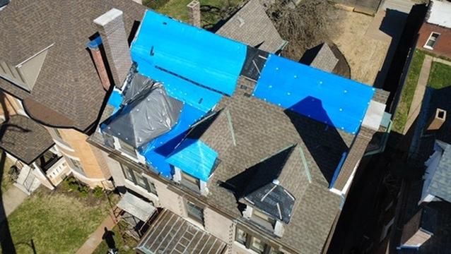 Storm-damaged roof tarped over and stripped to the decking during replacement by Emmendorfer Exteriors in Franklin County, MO, drone view